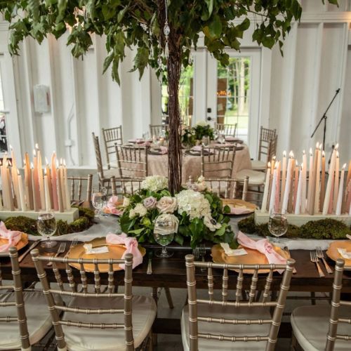 Tables set up for a wedding. Table with a  tree and flowers and many multi layers of neutral colored candels 